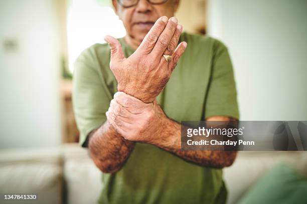 shot of a senior man experiencing wrist pain - arthritis stockfoto's en -beelden