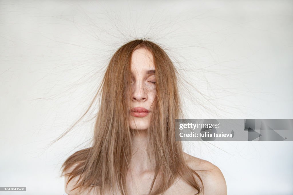 Serene woman with electrified hair on white background