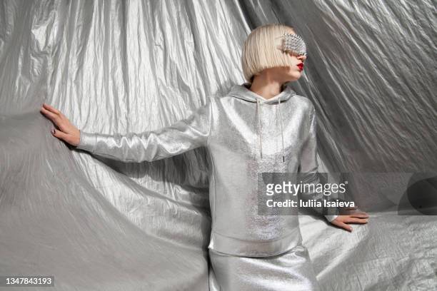 fashionable woman in gray silver outfit with silver background - metallic dress stock-fotos und bilder