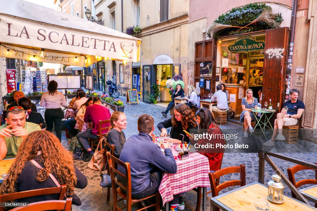 Dozens of tourists enjoy life in a typical Italian restaurant in the Trastevere district in the heart of Rome