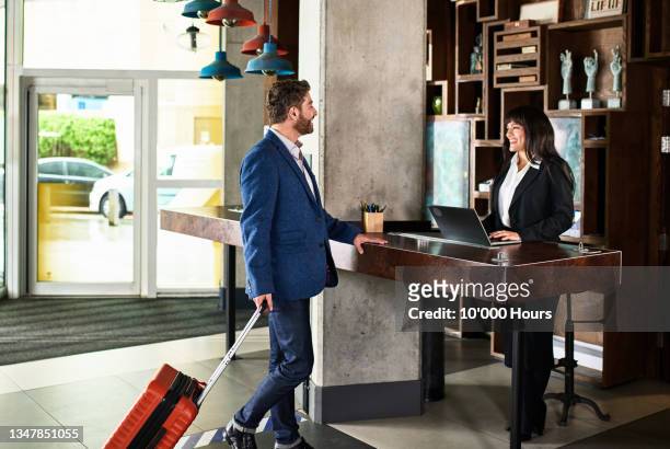 Businessman with suitcase arriving at hotel reception
