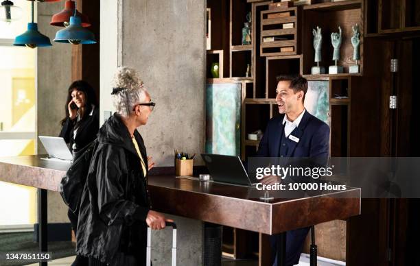 cheerful male receptionist serving woman in hotel - welcoming guests foto e immagini stock