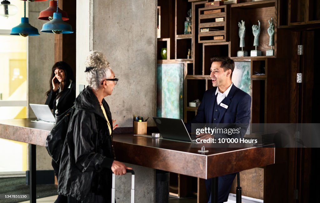 Cheerful male receptionist serving woman in hotel