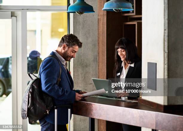 businessman arriving in hotel for conference at reception desk - bürorezeption stock-fotos und bilder