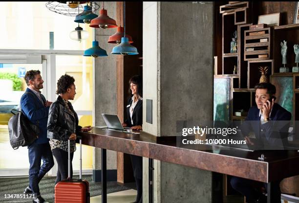 businessman and woman checking in to hotel reception - airport staff stockfoto's en -beelden