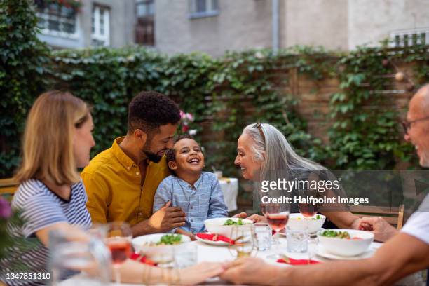 portrait of multiracial three generations family having dinner together outdoors in front or back yard. - bbq father stock-fotos und bilder