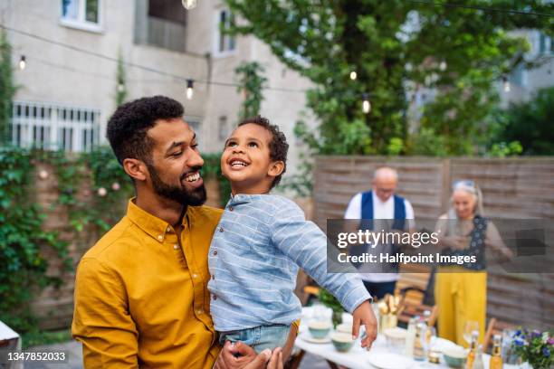 happy father holding his small son during family dinner outdoors in garden. - stili di vita foto e immagini stock
