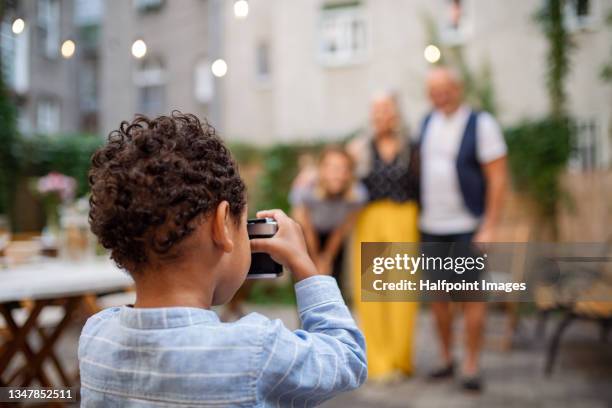 close up of little african - american boy taking photograph of his mother and grandparents outdoors in front or back yard. - up front party stock pictures, royalty-free photos & images