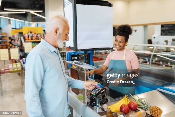 employee in supermarket serving senior customer - supermarket cashier stock pictures, royalty-free photos & images