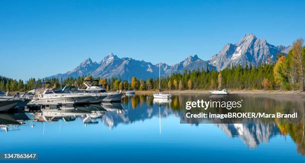 mountains reflected in the lake, jackson lake, sailboats and motorboats in a bay, colter bay in autumn, teton range mountain range, grand teton national park, wyoming, usa - colter bay stock pictures, royalty-free photos & images