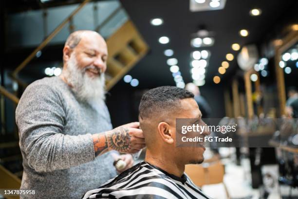 hairdresser cutting the hair of a young man at the barber shop - barberare bildbanksfoton och bilder