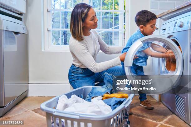 shot of a little boy helping his mother load the laundry into the washing machine - hushållssyssla bildbanksfoton och bilder