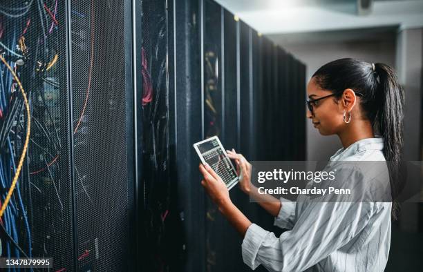 shot of a young woman using a digital tablet while working in a server room - information security imagens e fotografias de stock