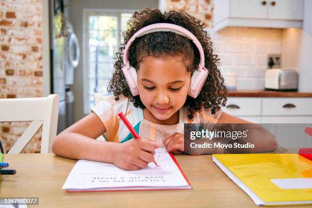 shot of a little girl wearing headphones while completing her school work - kid headphones stock pictures, royalty-free photos & images