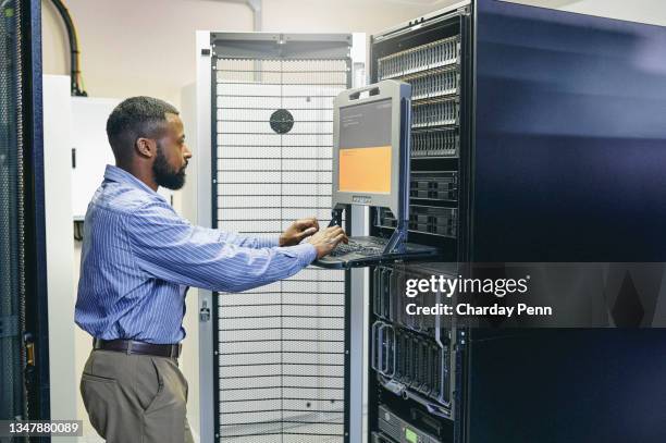 shot of a young man working on a computer in a server room - old computer equipment stock pictures, royalty-free photos & images