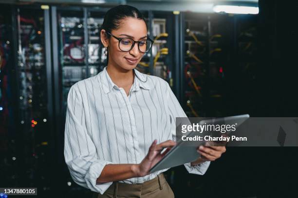 shot of a young woman using a digital tablet while working in a server room - computersoftware stockfoto's en -beelden