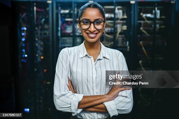 portrait of a young woman standing with her arms crossed while working in a server room - computer network technician stock pictures, royalty-free photos & images