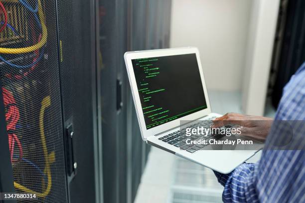 primo piano di un uomo irriconoscibile che usa un laptop mentre lavora in una sala server - byte foto e immagini stock