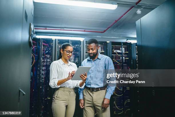 shot of two young technicians using a digital tablet while working in a server room - computer server stock pictures, royalty-free photos & images