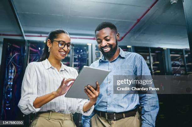 aufnahme von zwei jungen technikern mit einem digitalen tablet bei der arbeit in einem serverraum - it support stock-fotos und bilder