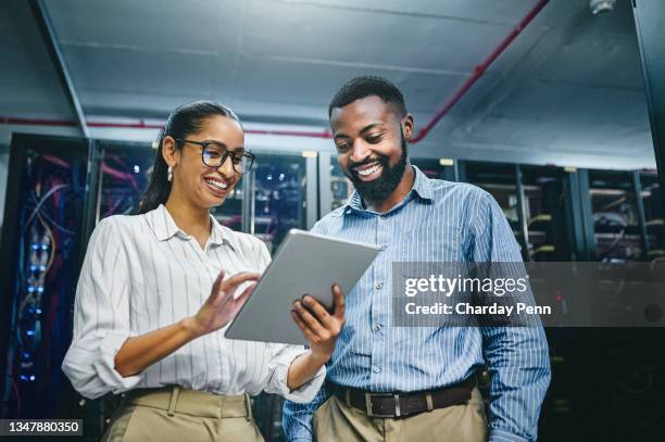 aufnahme von zwei jungen technikern mit einem digitalen tablet bei der arbeit in einem serverraum - technology stock-fotos und bilder