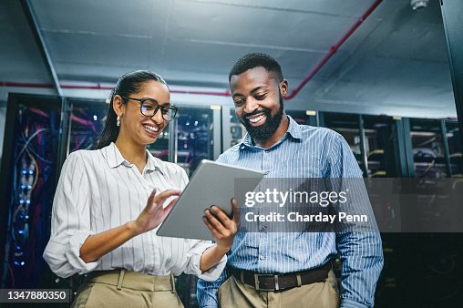 Toma de dos jóvenes técnicos usando una tableta digital mientras trabajaban en una sala de servidores Toma de dos jóvenes técnicos usando una tableta digital mientras trabajaban en una sala de servidores