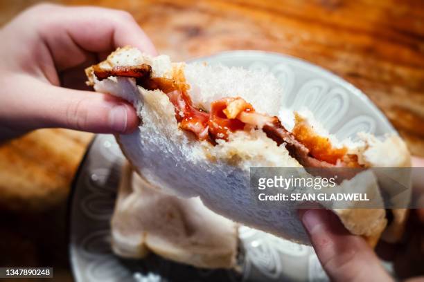 child eating a bacon sandwich - white bread stockfoto's en -beelden