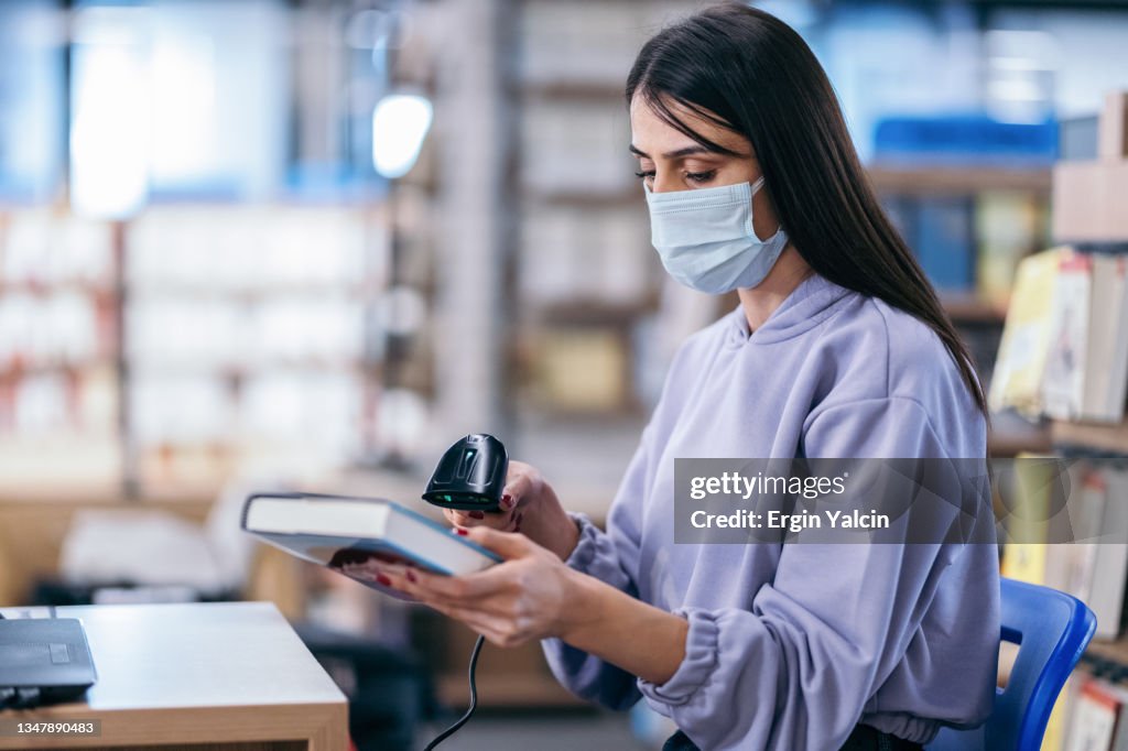 University Student Scanning A Book In Library High-Res Stock Photo ...