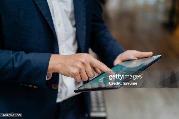 asiatischer geschäftsmann überprüft börsenchart auf digitalem tablet - computer closeup stock-fotos und bilder