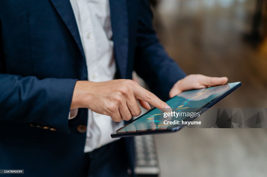 Empresário asiático verificando gráfico do mercado de ações em tablet digital