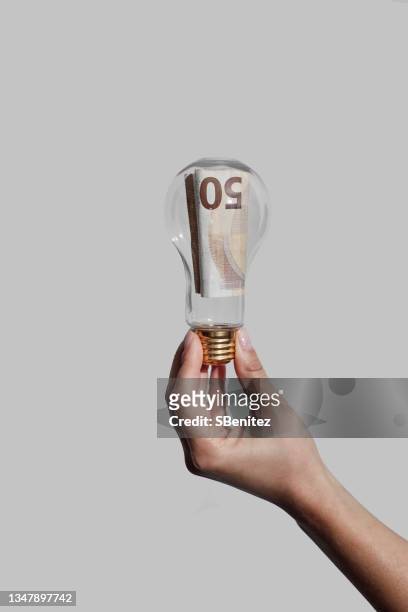 a € 50 bill inside a light bulb as a concept of rising electricity - inflation euro stockfoto's en -beelden