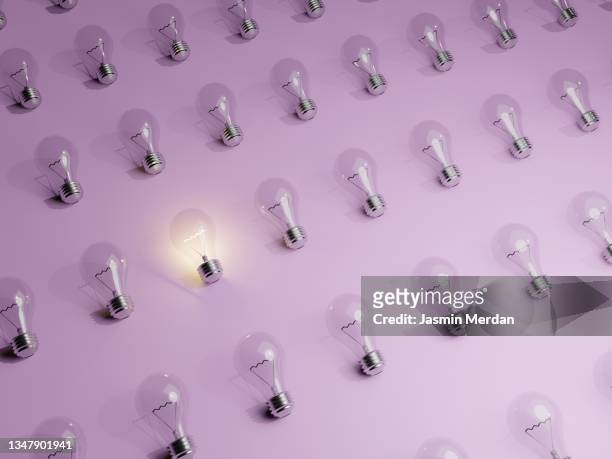 one light bulb standing out from the crowd - bombilla de bajo consumo fotografías e imágenes de stock