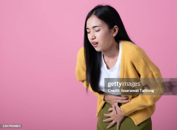 sad unhappy woman using hands touching belly position when she feeling painful suffering during menstruation period isolated on pink background. - stomachache fotografías e imágenes de stock