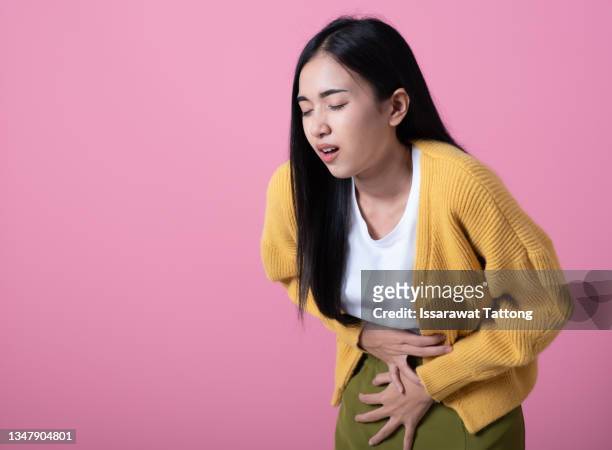 sad unhappy woman using hands touching belly position when she feeling painful suffering during menstruation period isolated on pink background. - dor de barriga imagens e fotografias de stock
