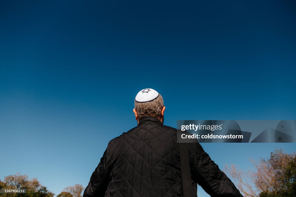 Rear view of Jewish man wearing skull cap looking at blue sky