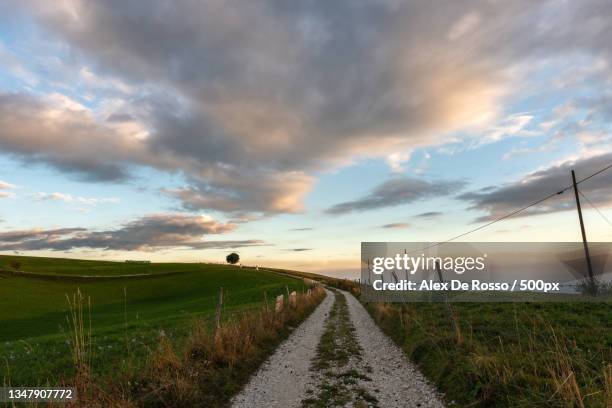 empty road amidst field against sky during sunset,asiago,vicenza,italy - asiago italy stock pictures, royalty-free photos & images