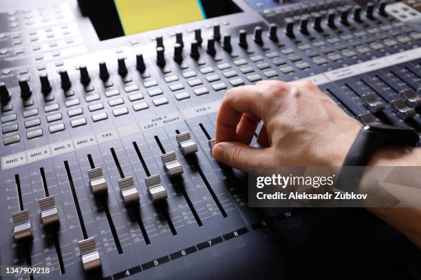 amplifying equipment. the man's hands switch and rearrange the handles of the studio audio mixer and faders. workplace and equipment of the sound engineer. acoustic music mixing, selective focus. - mixer foto e immagini stock