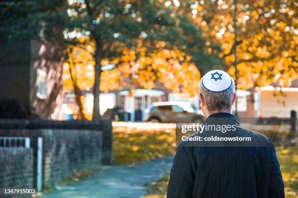 jewish man wearing skull cap walking on residential street - orthodox stock pictures, royalty-free photos & images