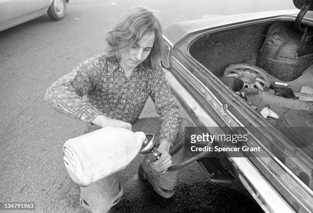 Motorist pours gas into a car from a jug during the oil crisis of 1973-74, Boston, Massachusetts, 1973.