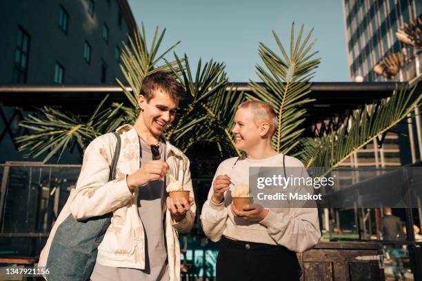 smiling male friends enjoying ice cream on sunny day - ice cream cup stock-fotos und bilder