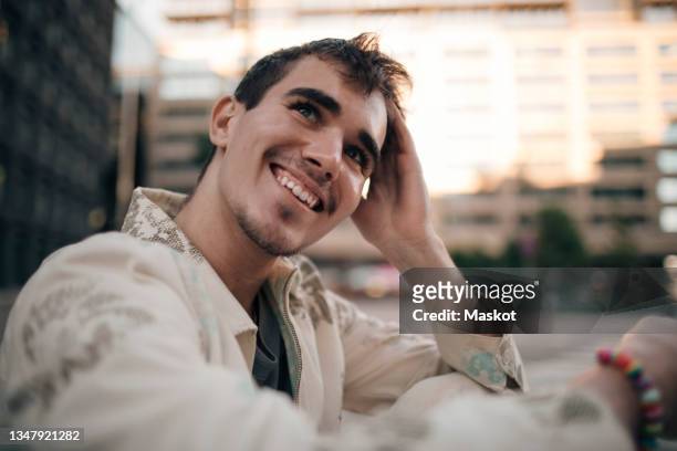 smiling man with hand in hair - wegsehen stock-fotos und bilder