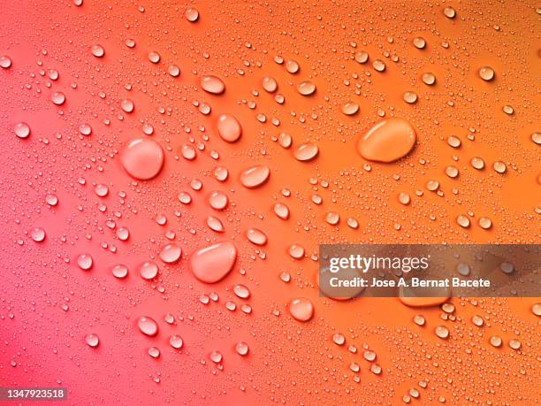 full frame of small drops and splashes of water on a orange  background. - dew texture stock pictures, royalty-free photos & images