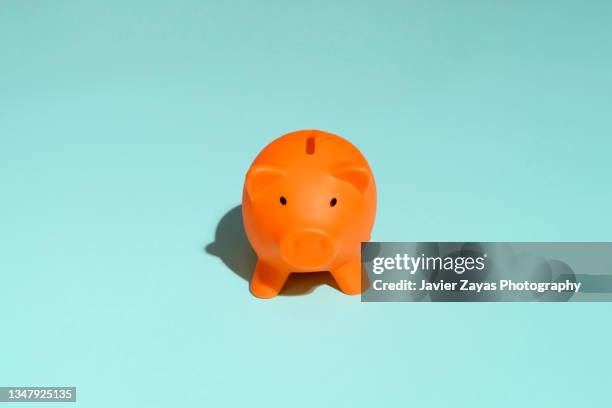 orange piggy bank on green background - orange piggy bank stock pictures, royalty-free photos & images