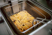 Close-up of fries in deep fryer. Restaurant meal preparation, side dish