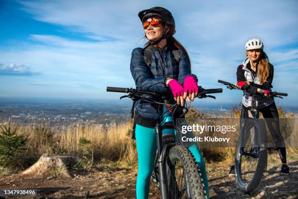 dos mujeres jóvenes en un paseo en bicicleta eléctrica - mountain biking fotografías e imágenes de stock