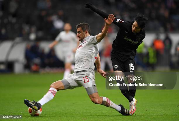 Sokratis Papastathopoulos of Olympiakos is challenged by Daichi Kamada of Eintracht Frankfurt during the UEFA Europa League group D match between...