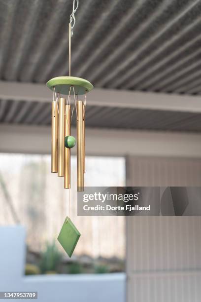 green and golden wind chime in wood and metal with a blurred background - vindspel bildbanksfoton och bilder
