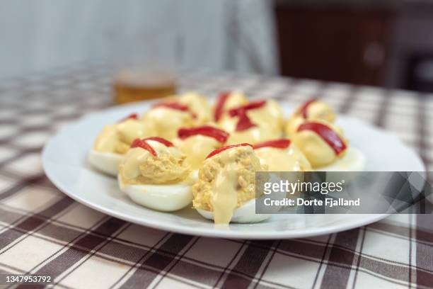 a plate with homemade stuffed eggs on a brown and white checkered tablecloth - hard boiled eggs stock-fotos und bilder