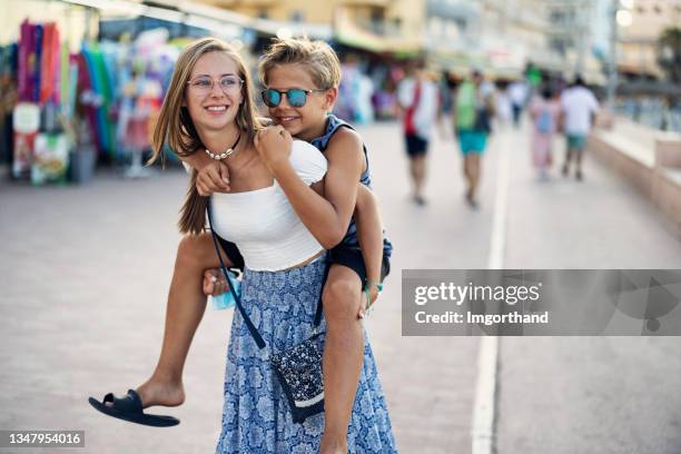 sister carrying brother on a summer vacations day - brother sister stock pictures, royalty-free photos & images