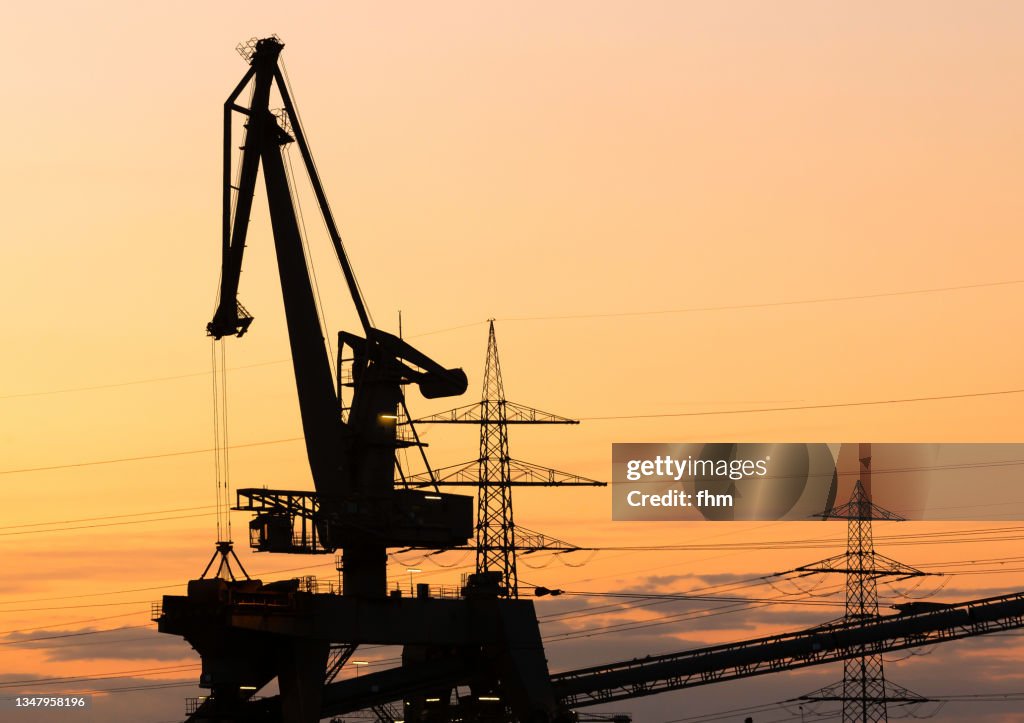 Coal crane and electricity pylons at sunset